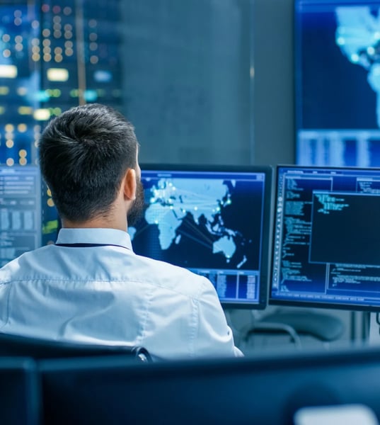 man sitting down looking at cyber security reports and screens man sitting down looking at cyber security reports and screens